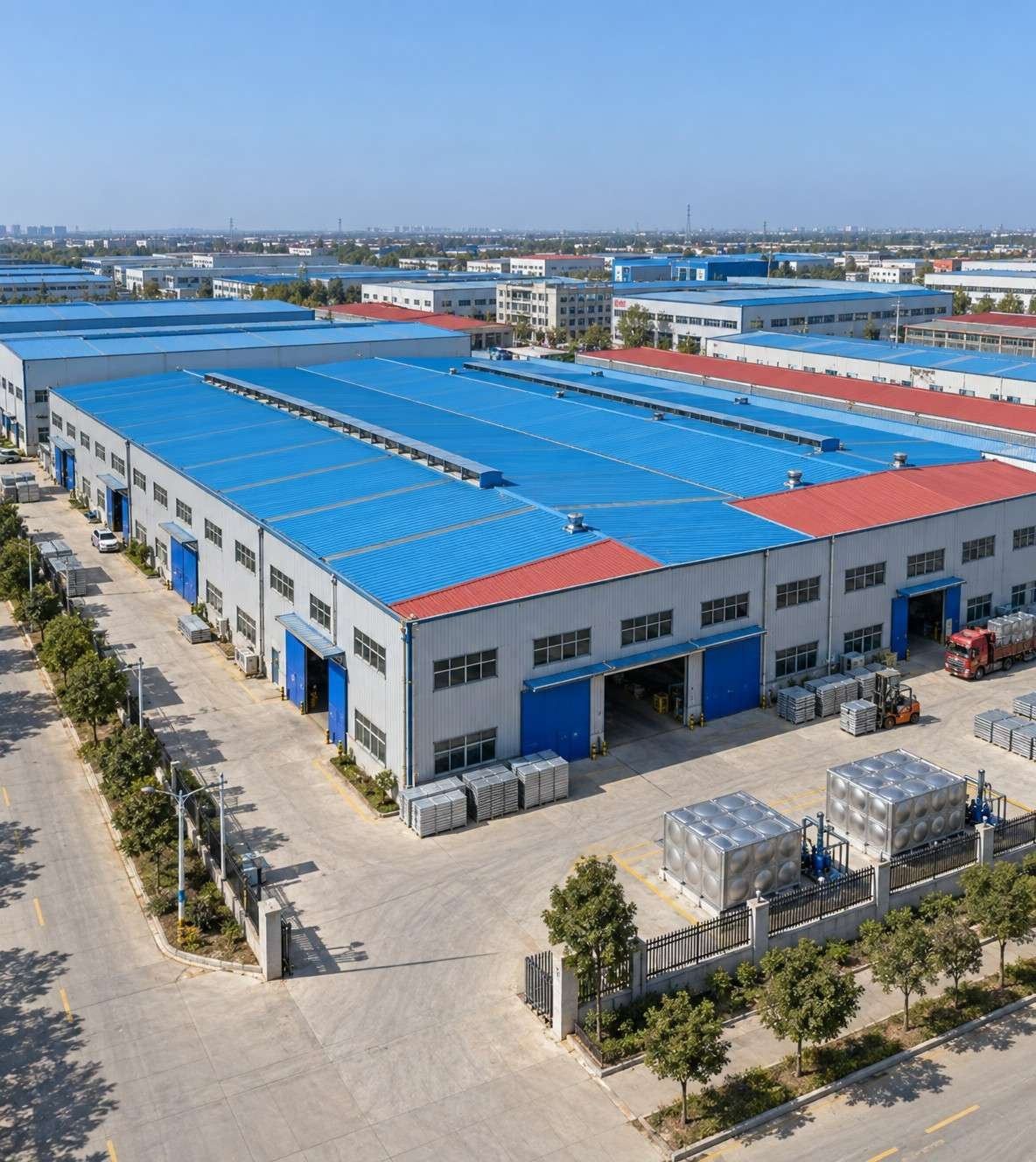 Aerial view of the LVJIA water tank factory in Dezhou, China, with blue-roof workshops and finished tanks in the yard